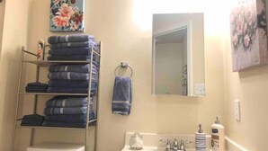 Un baño con inodoro, lavamanos y un perchero con toallas dobladas.
