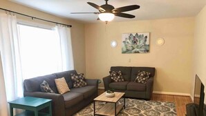 A living room with two sofas, a coffee table, a TV, and a ceiling fan.