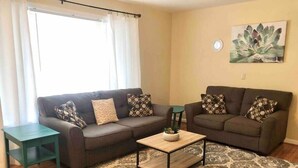 A living room with two sofas, a coffee table, and a patterned rug.