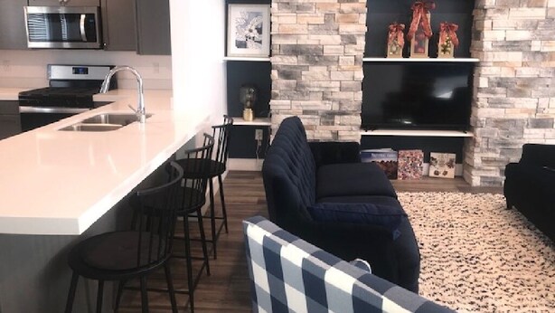 A modern kitchen with a central island, bar stools, and a stone accent wall.