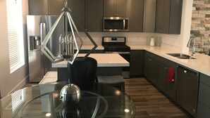 A modern kitchen with a central island, stainless steel appliances, and a stone accent wall.