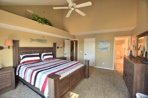 A bedroom with a large bed, wooden headboard, a ceiling fan, a dresser, and a door leading to another room. - Breathtaking view! 2 Pools & Beach - 4 Enclosed Bedrm/3 bth/40'  BoatSlip Avlb. (Osage Beach)