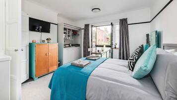 Ein Schlafzimmer mit Bett, Kleiderschrank, Schreibtisch und einem Fenster mit Vorhängen.