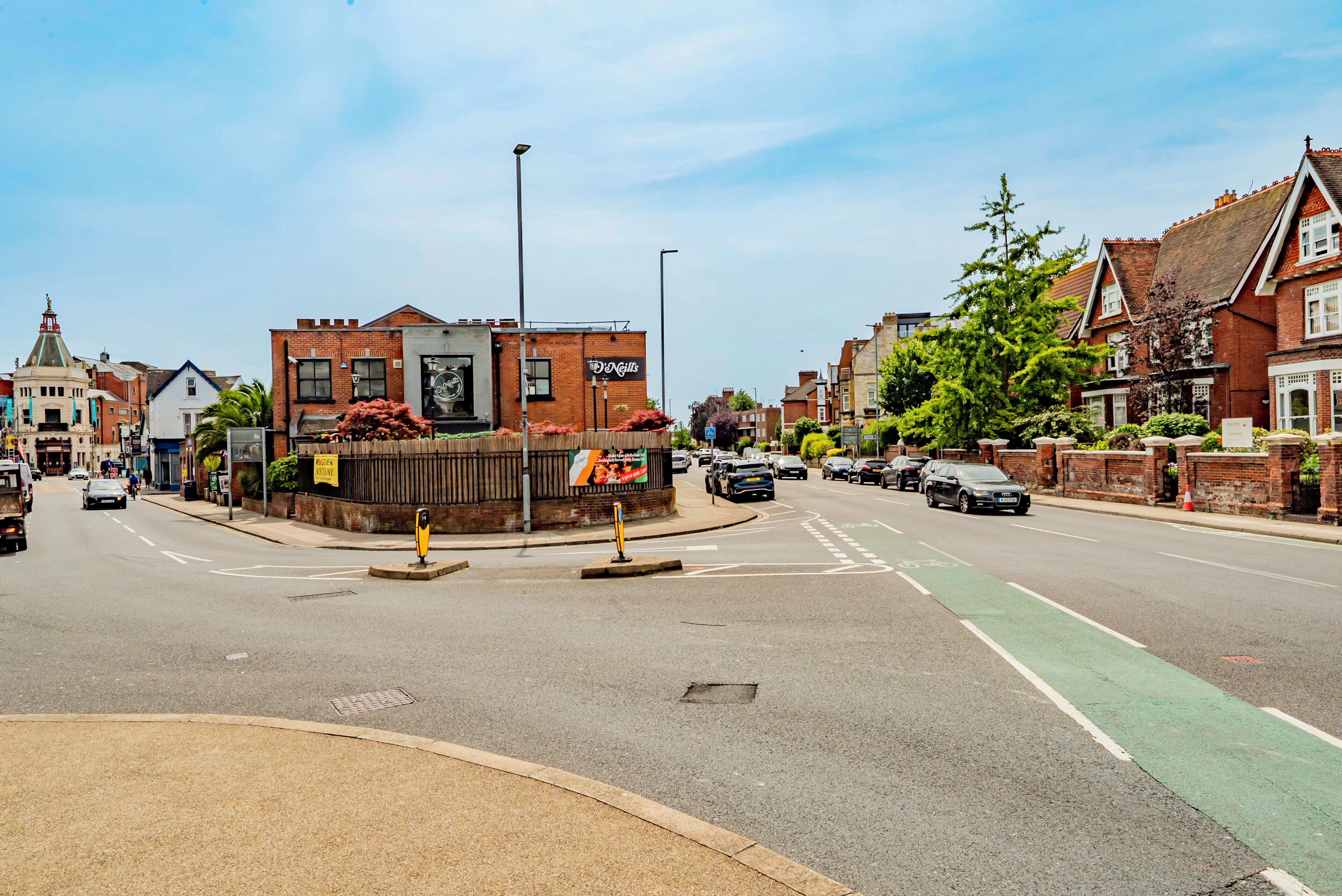 A street with buildings, a roundabout, and a green bike lane.