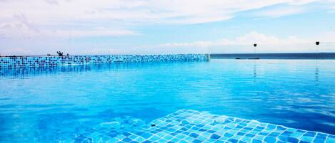 Una piscina al aire libre, sillones reclinables de piscina