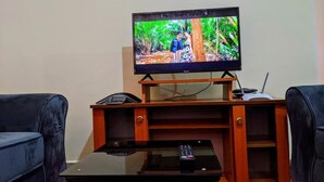 Una televisione su un supporto in legno con un telecomando su un tavolino di vetro di fronte.