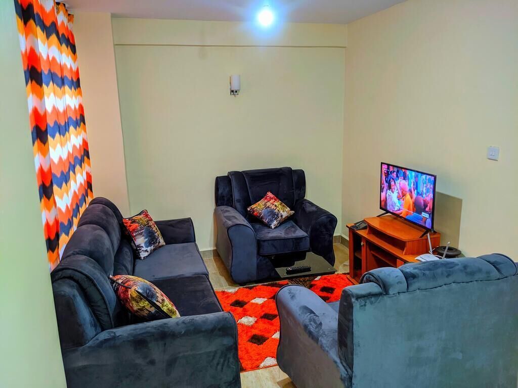 A living room with two sofas, a TV, and a red rug.