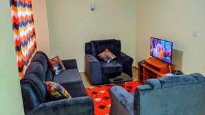 Un soggiorno con due divani, una televisione e un tappeto rosso.