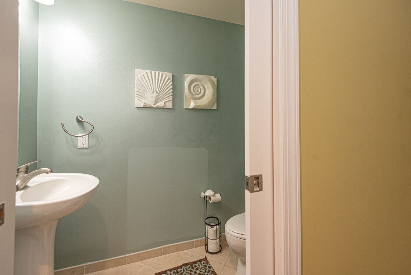 A bathroom with a sink, toilet, and two wall-mounted artworks.