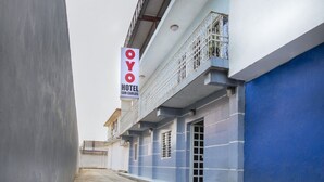 Un hôtel appelé OYO, reconnaissable à son panneau indicateur, à sa façade bleue et à son balcon doté de rampes en métal.