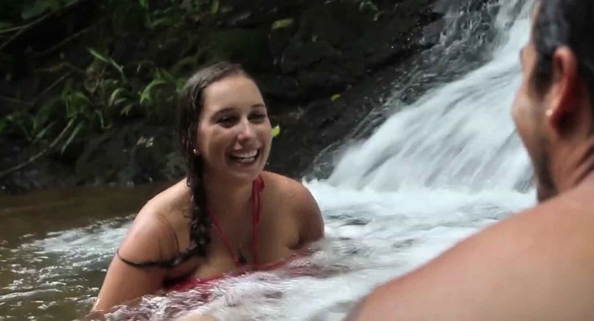 Una persona in un ambiente naturale con una cascata sullo sfondo.