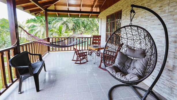 A covered outdoor area with a wooden ceiling, a hammock, a rocking chair, and a hanging chair with cushions. - Casa Naranjito (Naranjito)