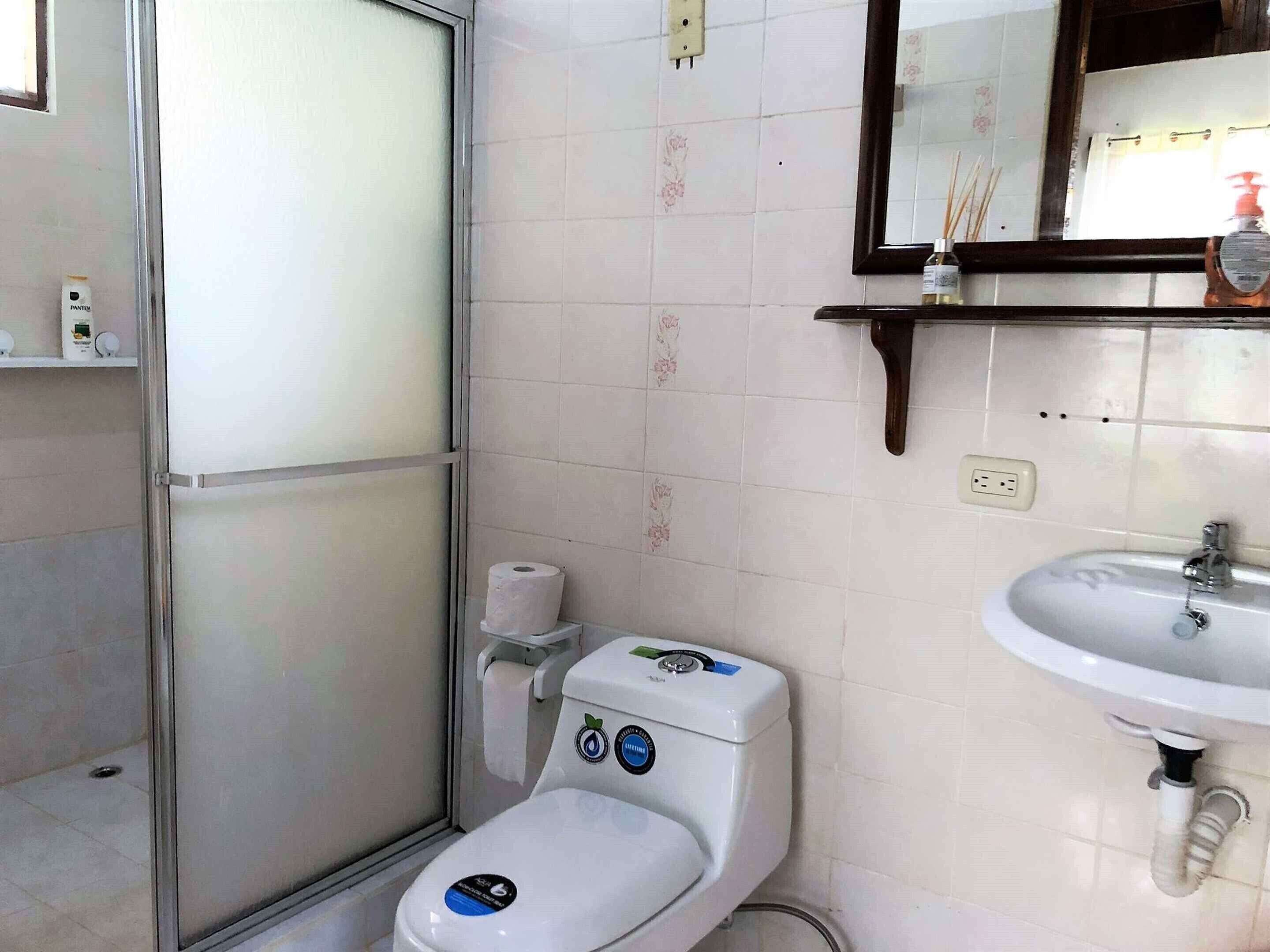 A bathroom with a toilet, a sink, and a mirror.