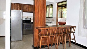A kitchen with wooden cabinets, a stainless steel refrigerator, an oven, and a wooden dining table with chairs. - Casa Naranjito (Naranjito)