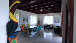 A dining area with a table and chairs, a sofa, and a large bird sculpture. - Casa Naranjito (Naranjito)