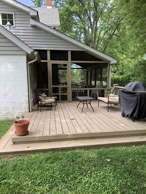 A covered outdoor deck with a grill, seating, and a potted plant. - Sailors Crossing (Rock Hall)