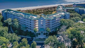 A multi-story hotel with a central courtyard, surrounded by lush greenery and a beachfront view. - Family Villa | Ocean/Pool Views, Balcony, Bikes, Close to Shops/Dining (Hilton Head Island)