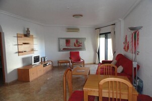 Una sala de estar con un mueble de televisión de madera, un sillón rojo y un sofá rojo.