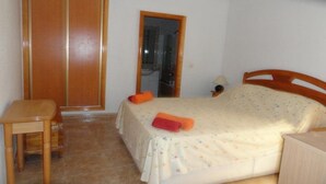 Ein Schlafzimmer mit einem Bett, einem Holzstuhl, einem Kleiderschrank und einem kleinen Tisch.