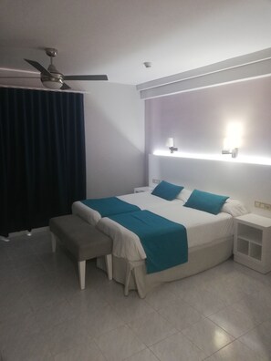 A modern bedroom with a large bed, bedside tables, a bench, a ceiling fan, and a wall-mounted light fixture. - Oceano Apartments - Adults Only (Teguise)