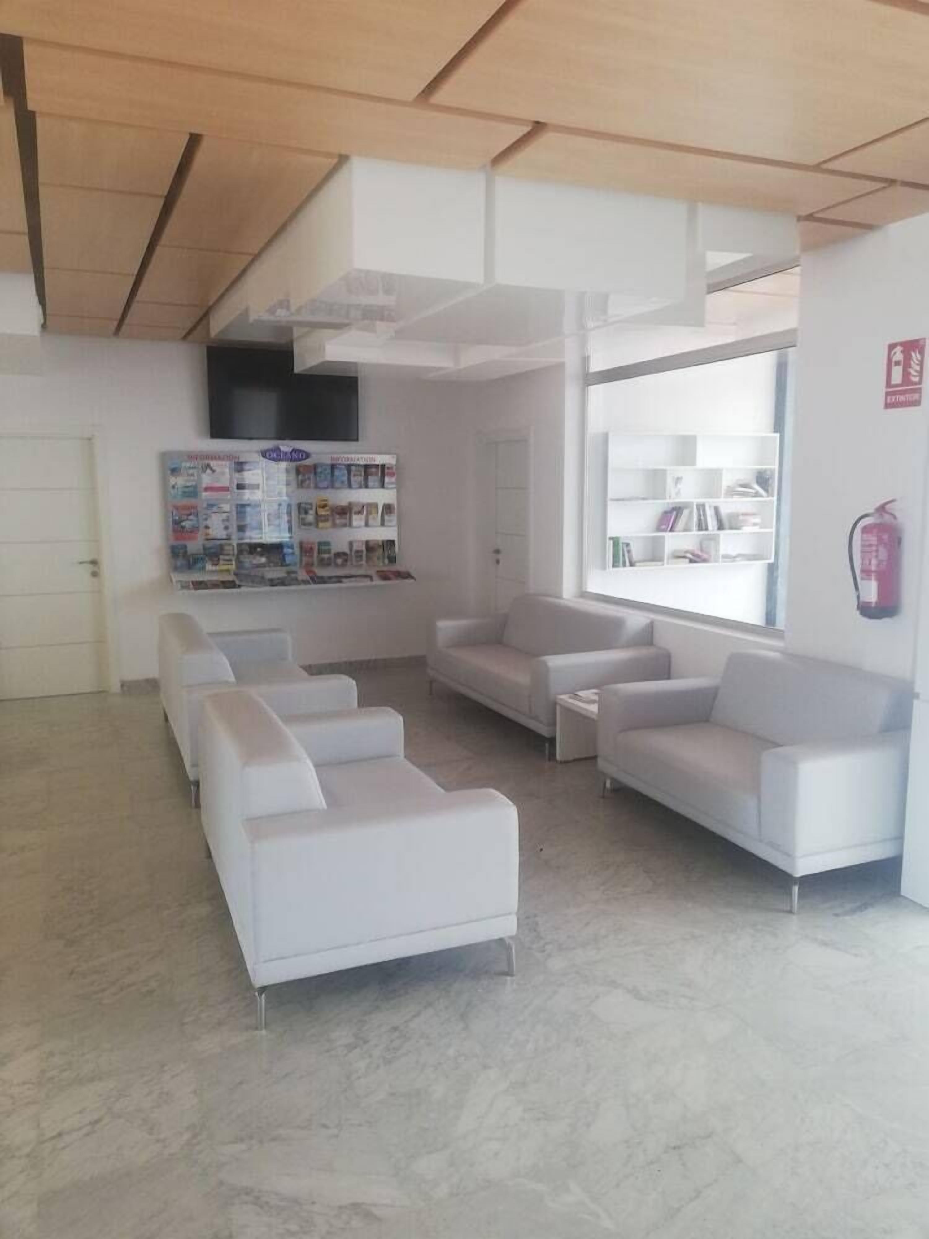 A modern waiting area with white sofas and a bulletin board.
