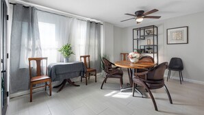 A dining area with a round wooden table, four chairs, a ceiling fan, and a bookshelf with decorative items. - 》Hip Urban Getaway Next to Downtown, with Firepit, 3 Bedrooms, Sleeps 6《 (TAMPA)