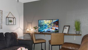 A living room with a flat-screen TV, two leather sofas, a coffee table, and decorative items including a vase with flowers and a framed certificate. - 》Hip Urban Getaway Next to Downtown, with Firepit, 3 Bedrooms, Sleeps 6《 (TAMPA)