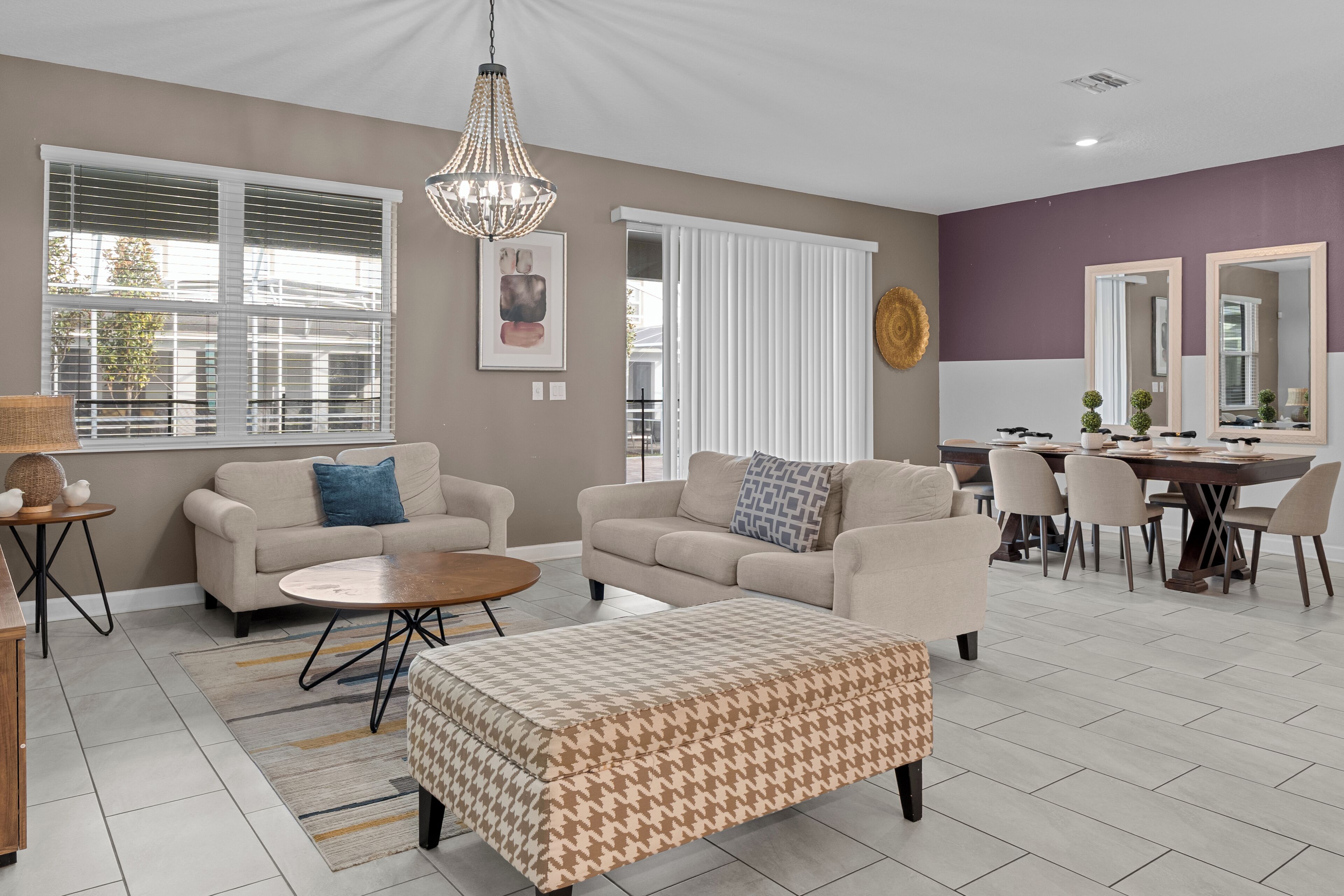 A modern living room with a sofa, ottoman, and dining area with chairs and a table.