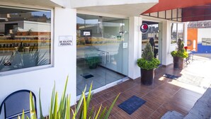 A modern building entrance with glass doors, a reception area, and potted plants. - Capital O Plaza Galindo (San Juan de los Lagos)