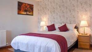 Ein Schlafzimmer mit einem Bett, zwei Nachttischlampen, einer Heizung und einer Wand mit Wandpapier mit einem Hirschmuster.