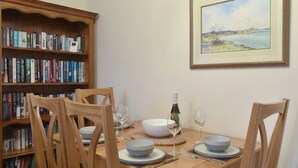 A dining table with four chairs, a wine bottle, and glasses, surrounded by bookshelves. - 2 bedroom accommodation in Knipe Point, near Cayton (Knipe Point, near Cayton)