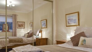 A hotel room with a large mirror, two beds, a bedside table with a lamp, and a framed picture on the wall. - 2 bedroom accommodation in Knipe Point, near Cayton (Knipe Point, near Cayton)