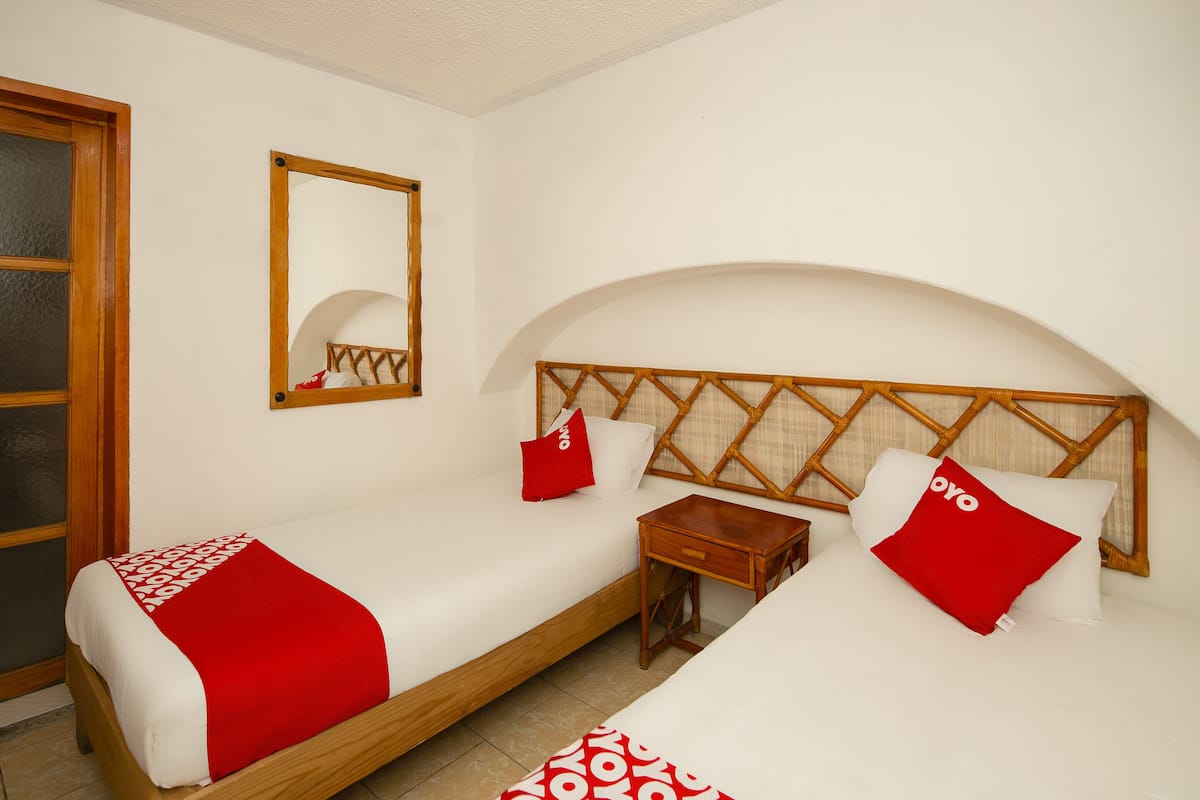 A double bed with a wooden headboard, a bedside table, and a red pillow.