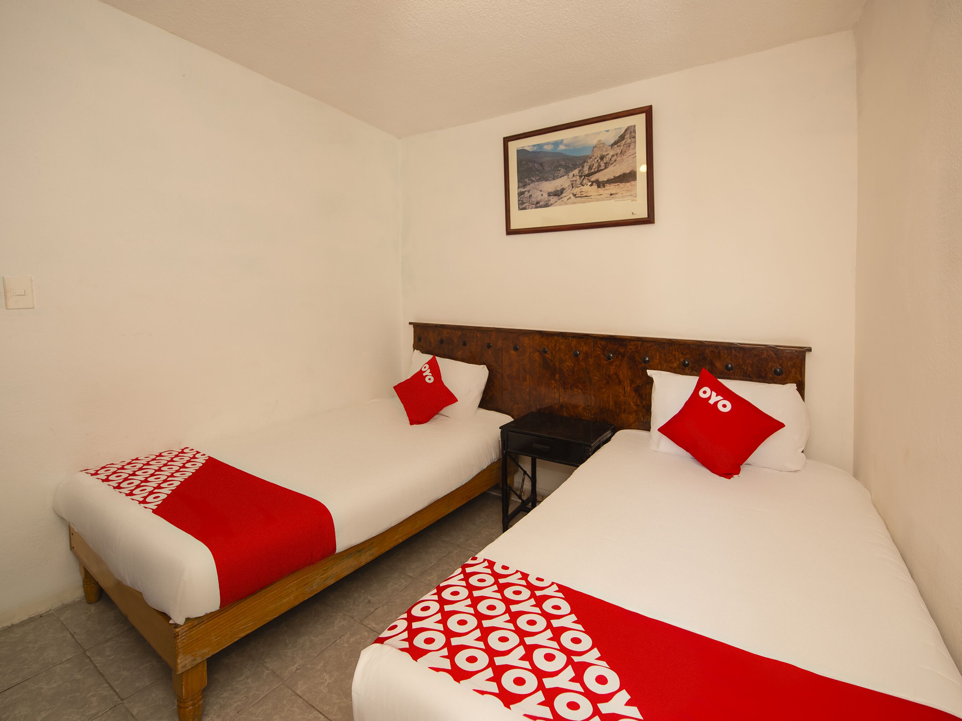 Two single beds with wooden frames, white bedding, and red accents.
