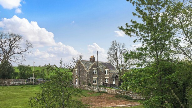 A stone house with a sloped roof, surrounded by a grassy field and trees. - 2 bedroom accommodation in Kirkby stephen (Kirkby stephen)
