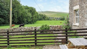 A stone building with a window, a wooden fence, and a picnic table. - 2 bedroom accommodation in Kirkby stephen (Kirkby stephen)