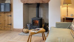 A cozy living room with a wood-burning stove, a television, a sofa, and a table with a magazine. - 2 bedroom accommodation in Kirkby stephen (Kirkby stephen)