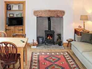 A cozy living room with a fireplace, wooden furniture, and a colorful rug.