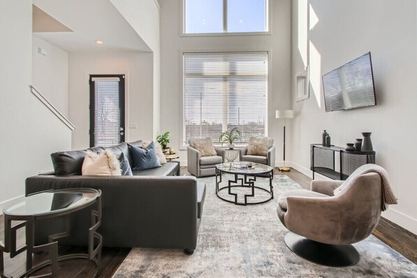 Un salon moderne avec un canapé gris, une table basse ronde et un fauteuil confortable.