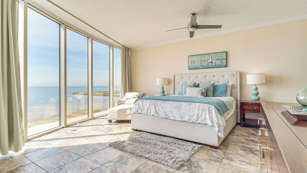 A bedroom with a large window, a bed, a nightstand, and a view of the ocean. - Walk to Beach: Luxury Biloxi Condo w/ Pool Access! (Biloxi)
