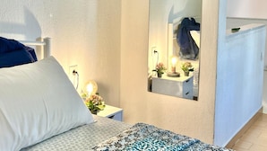 A bedroom with a bed, bedside table with a lamp, a mirror, and a dresser. - Nikiti Beach (Sithonia)