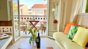 A living room with a sofa, a coffee table, and a view of a balcony with outdoor furniture. - Nikiti Beach (Sithonia)