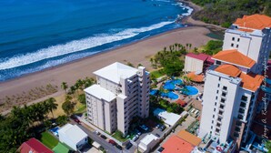 A coastal hotel with multiple buildings, a beach, and a swimming pool complex. - Ocean front and just steps from the pools and ocean! (Jacó)