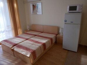 A bedroom with a double bed, a bedside table, a lamp, a wall-mounted picture, and a white refrigerator. - Marina View Fort Beach (Nessebar)
