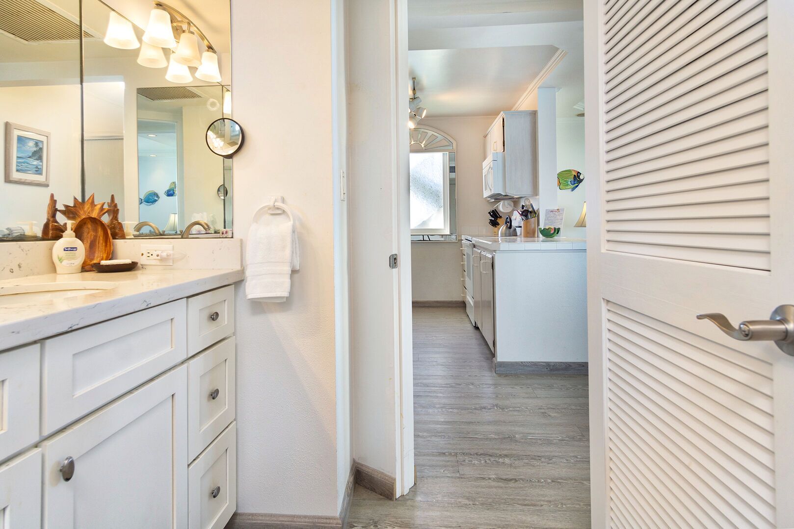 A modern bathroom with a large mirror, white cabinetry, and a towel rack.