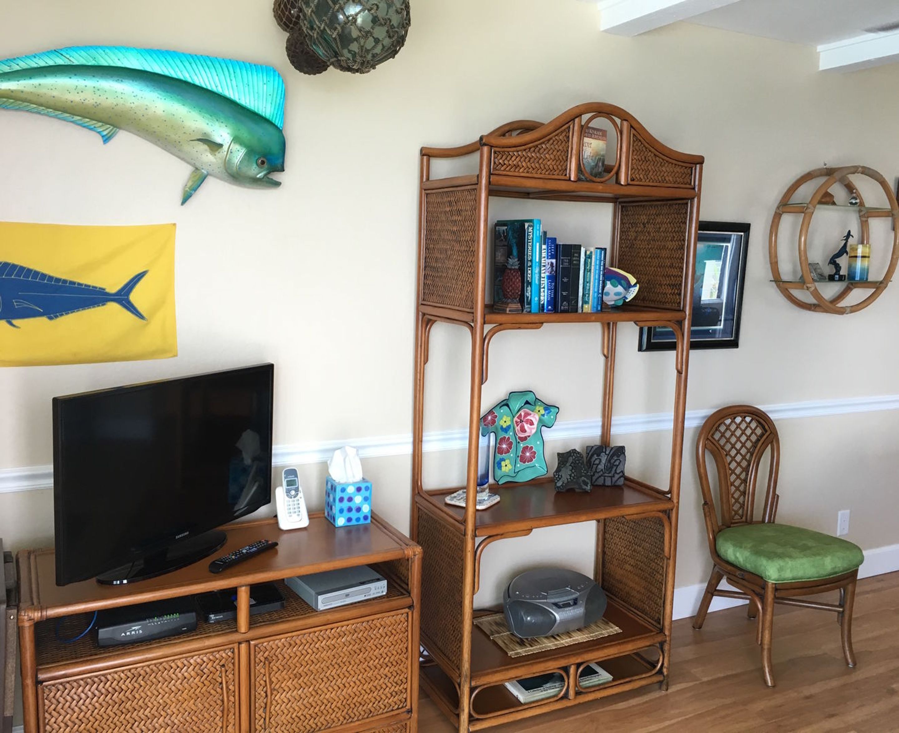 A living room with a television, a bookshelf, and a decorative fish on the wall.