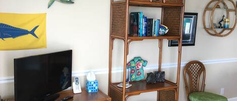 A living room with a television, a bookshelf, and a decorative fish on the wall.