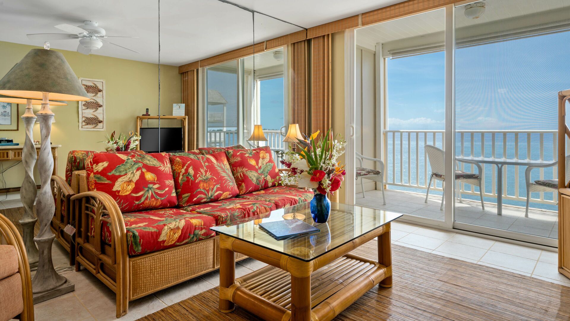 Ett rymligt vardagsrum med en soffa, ett soffbord i glas och utsikt över havet genom stora skjutdörrar.