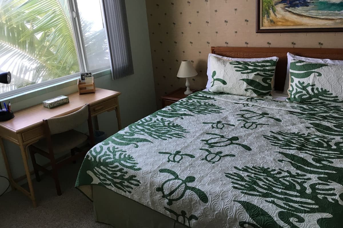 Ein Hotelzimmer mit Bett, Schreibtisch, Lampe und einem Bild an der Wand.