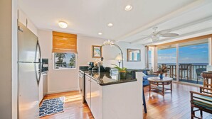 A modern kitchen with a central island, a dining area with a view, and a balcony with a view.
